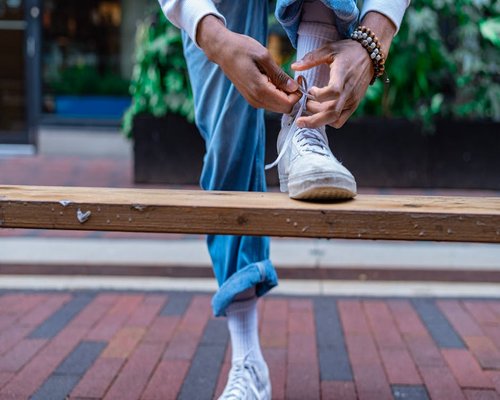 Person tying comfortable walking shoes on a city bench