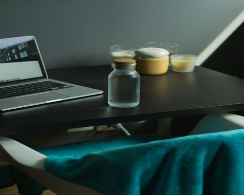 A glass of water and a notebook on a desk next to an ergonomic chair